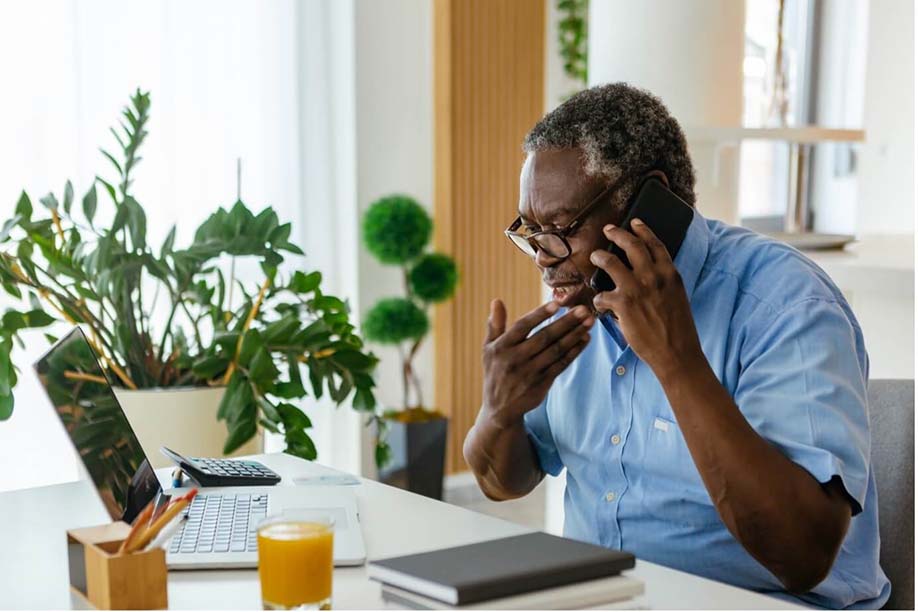 An elderly individual on a phone call at a desk