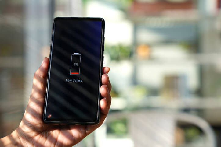 Hand holding phone with low battery icon on screen